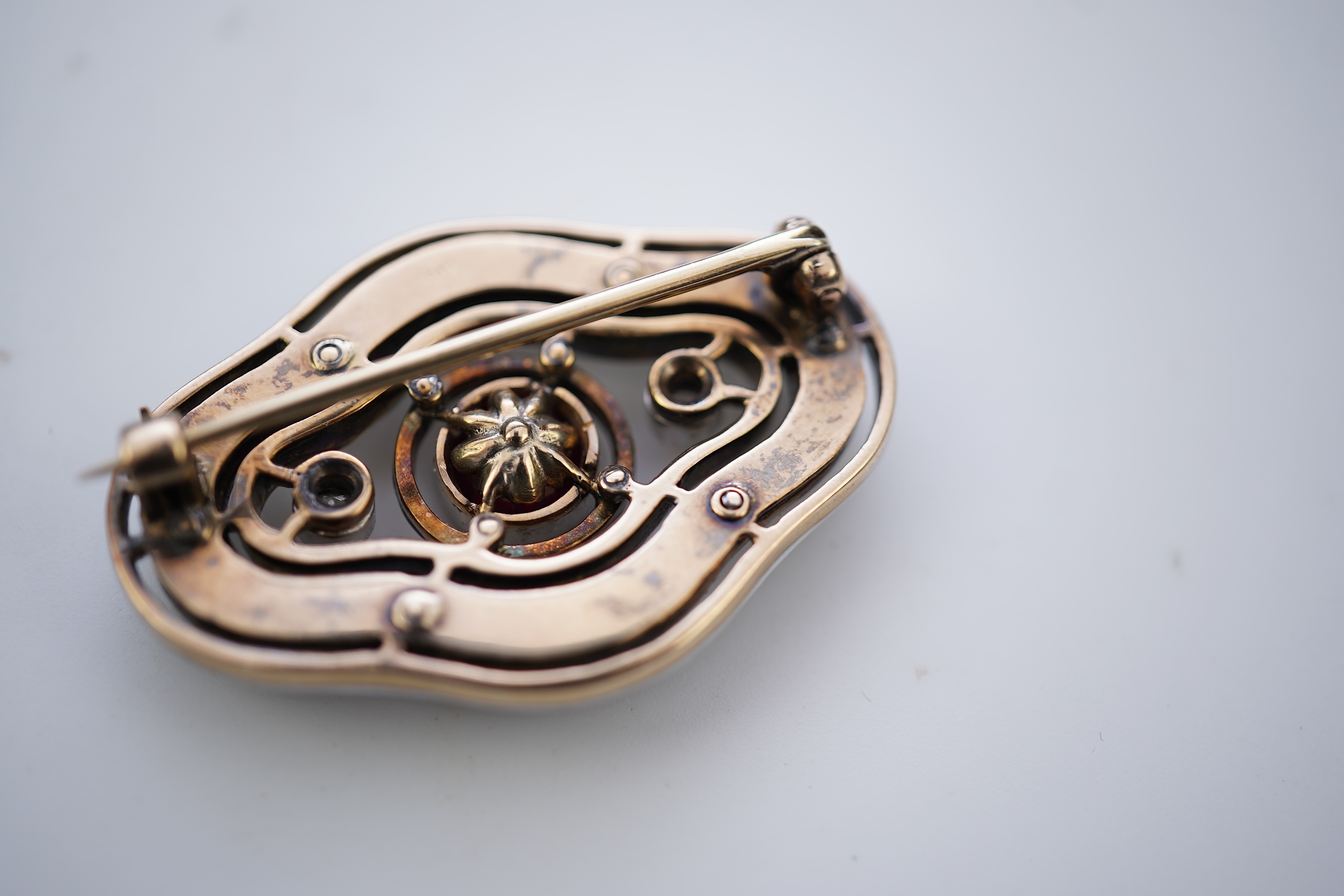 An unusual Art Deco onyx, enamel, ruby and diamond brooch, circa 1920